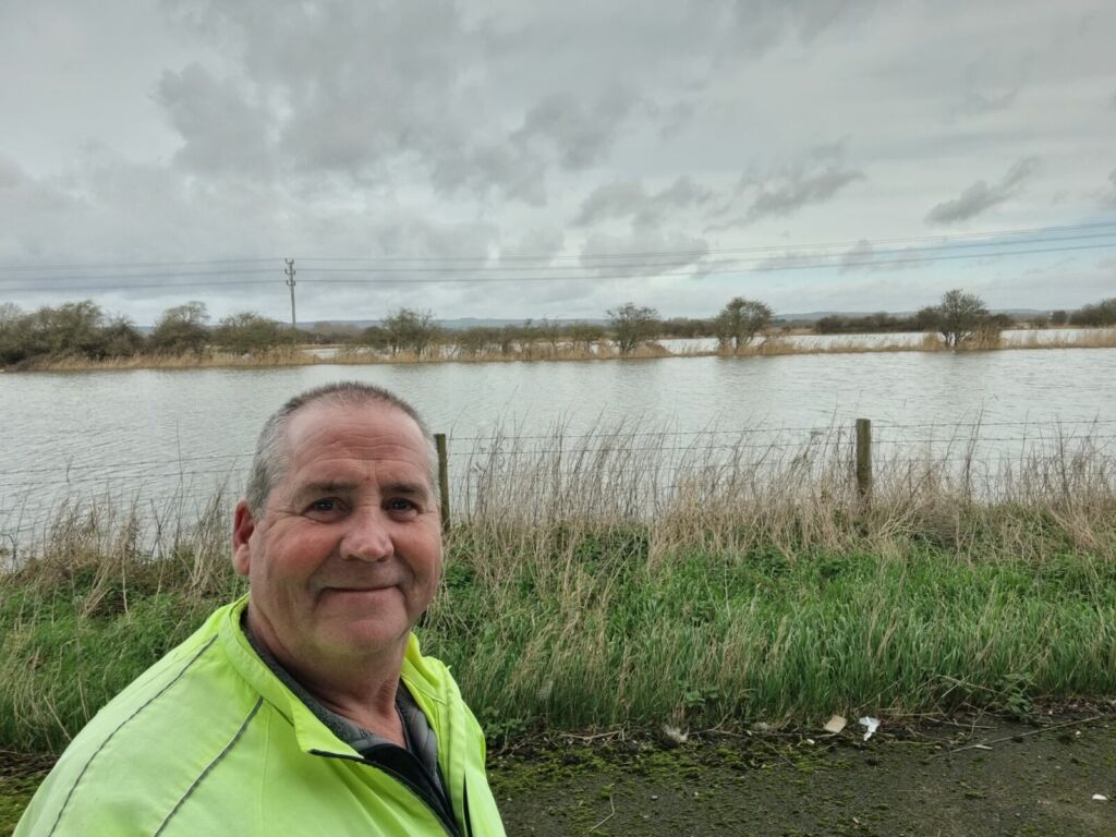 Man standing by a flooded field